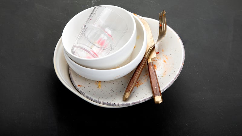Pile of empty and dirty plates with food leftovers on dark background.