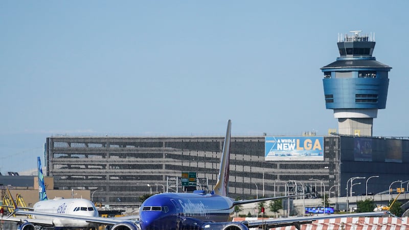 FILE - LaGuardia Airport's air traffic control tower, right, is shown as planes line-up for...