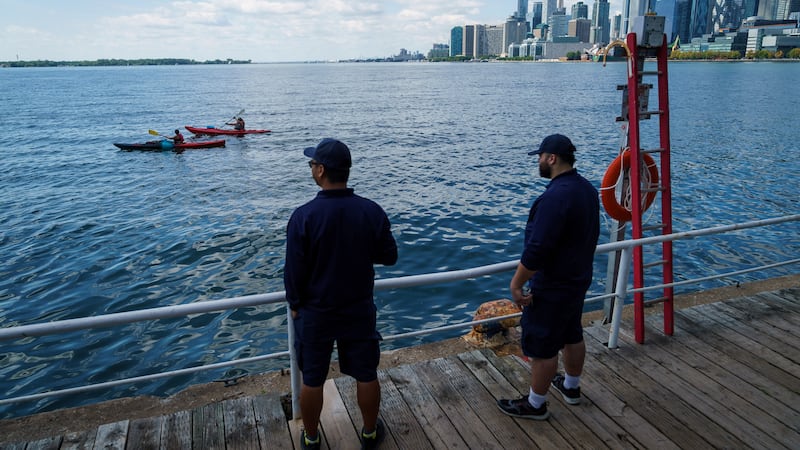 People look out across Lake Ontario from the harbor in Toronto, Tuesday, Aug. 25, 2026.