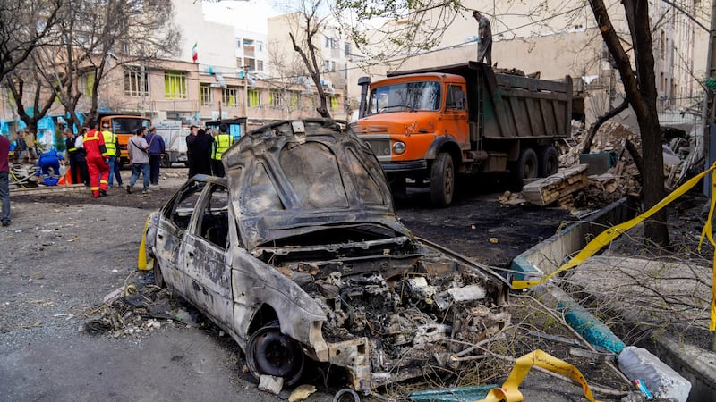 A damaged car remains on the ground in the aftermath of an Israeli-U.S. strike in Tehran,...