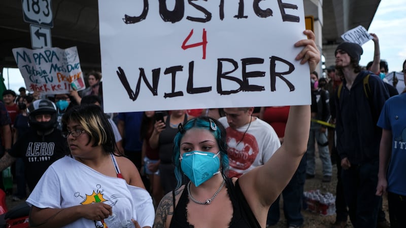 People speak during a demonstration where a man was shot in his vehicle by an ICE officer,...