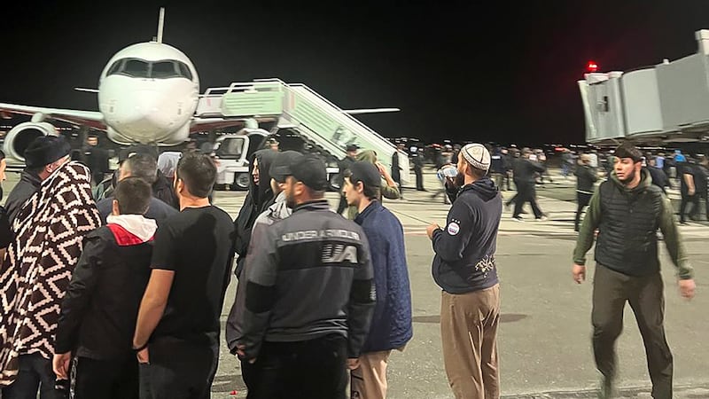 People in the crowd walk shouting antisemitic slogans at an airfield of the airport in...